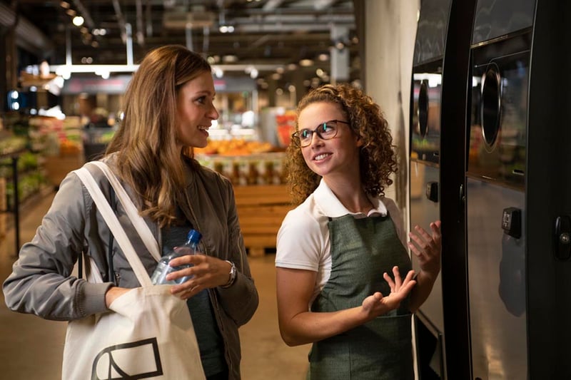 Women talking in front of a reverse vending machine