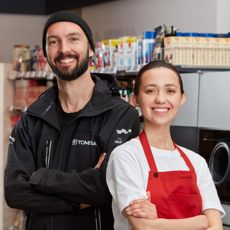 Two smiling shop staff in TOMRA aprons